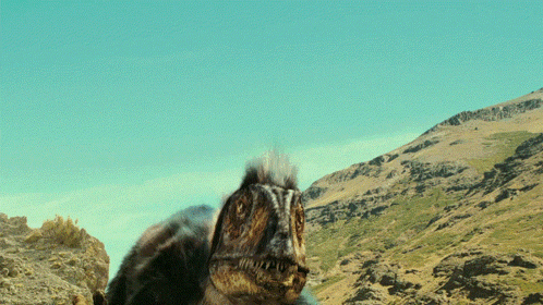 A Close Up Of A Lizard 'S Face With A Mountain In The Background GIF