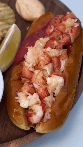 A Close Up Of A Lobster Roll On A Wooden Tray GIF