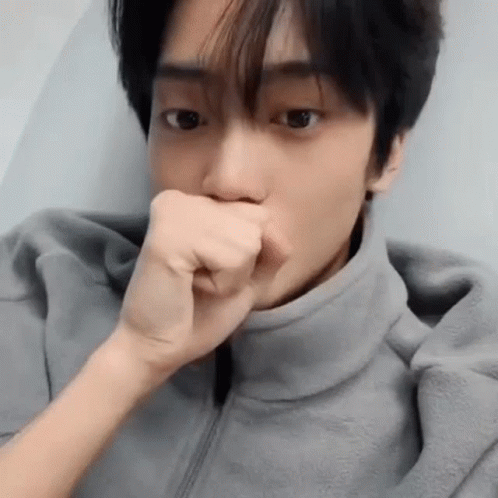 A Close Up Of A Man Covering His Mouth With His Fist . GIF