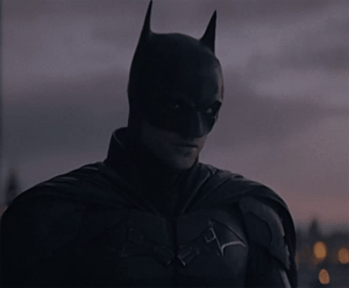 A Close Up Of A Man In A Batman Costume Looking At The Camera GIF