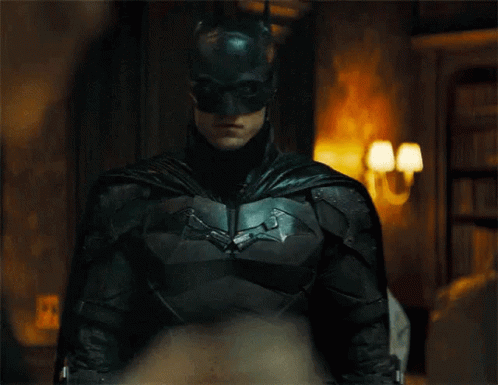 A Close Up Of A Man In A Batman Suit And Mask Standing In A Room . GIF