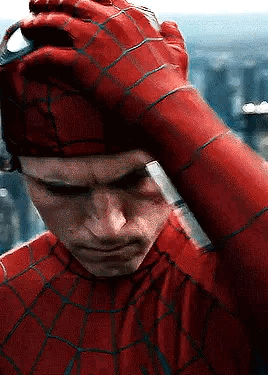 A Close Up Of A Man In A Spiderman Costume Holding His Hand To His Head . GIF