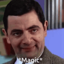 A Close Up Of A Man In A Suit And Tie With The Words `` Magic '' Written On His Face . GIF