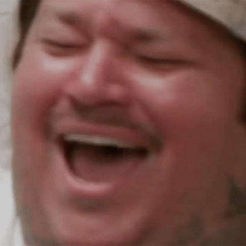 A Close Up Of A Man Laughing With His Eyes Closed And His Mouth Open . GIF