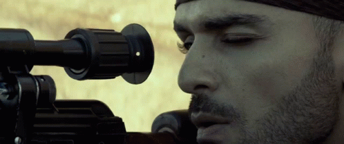 A Close Up Of A Man Looking Through A Sniper Rifle GIF