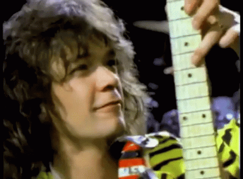 A Close Up Of A Man Playing A Guitar In A Dark Room . GIF