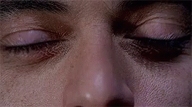 A Close Up Of A Man 'S Eyes With A Slight Smirk On His Face . GIF