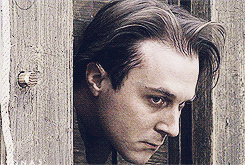 A Close Up Of A Man 'S Face Against A Wooden Fence GIF