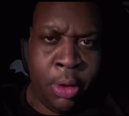 A Close Up Of A Man 'S Face In A Dark Room With His Hand On His Face . GIF