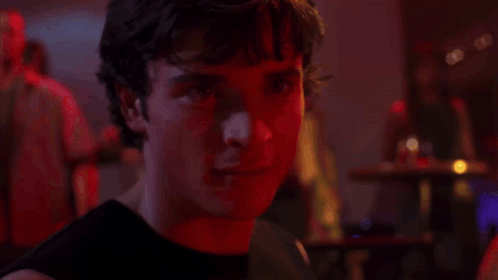 A Close Up Of A Man 'S Face In A Dark Room With Red Lights Behind Him . GIF