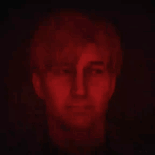 a close up of a man 's face in a dark room with red lights behind him .