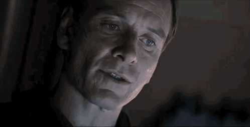 A Close Up Of A Man 'S Face In A Dark Room With Smoke Coming Out Of His Mouth . GIF