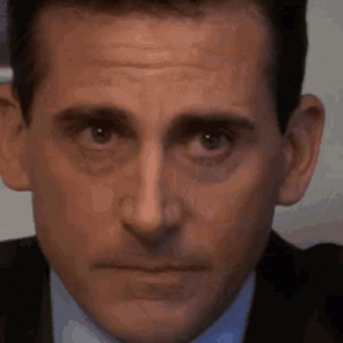 A Close Up Of A Man 'S Face In A Suit And Tie Making A Funny Face . GIF