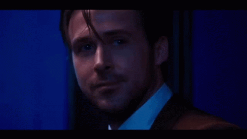 A Close Up Of A Man 'S Face In A Suit And White Shirt In A Dark Room . GIF