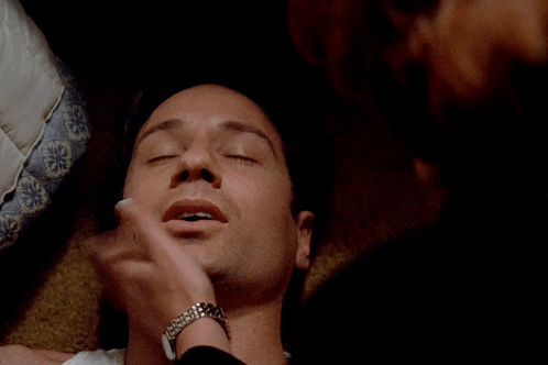 A Close Up Of A Man 'S Face Laying On A Bed GIF