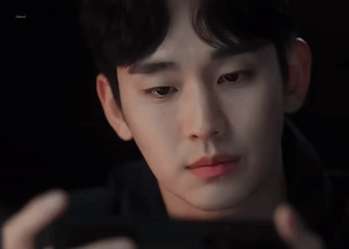 A Close Up Of A Man 'S Face Looking At A Cell Phone . GIF