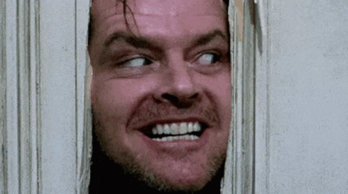 A Close Up Of A Man 'S Face Looking Through A Hole In A Wall . GIF