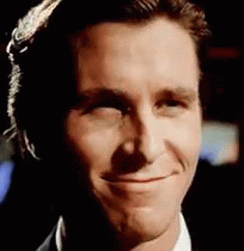 A Close Up Of A Man 'S Face Smiling While Wearing A Suit And Tie . GIF