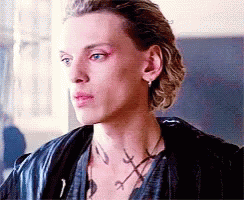 A Close Up Of A Man 'S Face Wearing A Leather Jacket And A Necklace . GIF