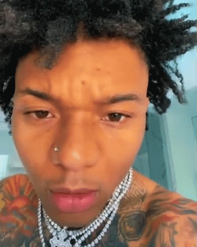 A Close Up Of A Man 'S Face Wearing A Necklace . GIF