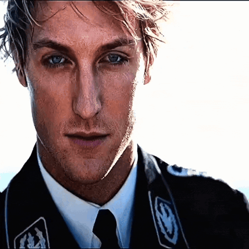 A Close Up Of A Man 'S Face Wearing A Suit And Tie With The Letter S On It GIF