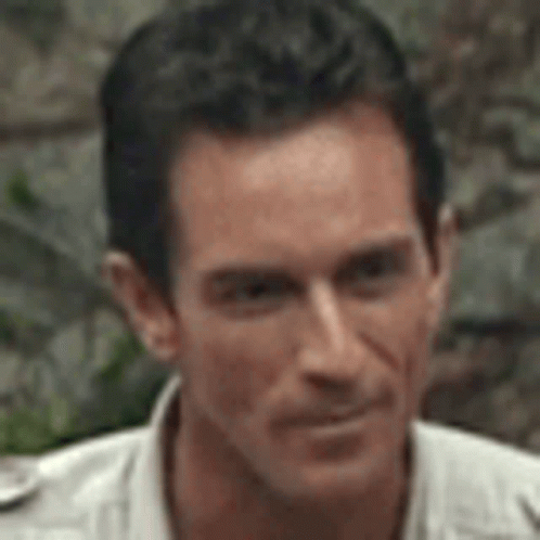 A Close Up Of A Man 'S Face Wearing A White Shirt And Looking At The Camera . GIF