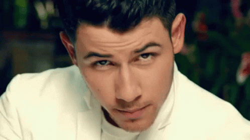 A Close Up Of A Man 'S Face Wearing A White Suit And Looking At The Camera . GIF