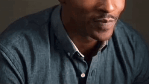 A Close Up Of A Man 'S Face With A Beard And A Blue Shirt . GIF