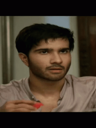 A Close Up Of A Man 'S Face With A Beard And A Pink Shirt GIF