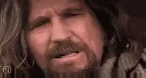 A Close Up Of A Man 'S Face With A Beard And Long Hair Making A Funny Face . GIF