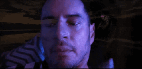 A Close Up Of A Man 'S Face With A Beard In A Dark Room GIF