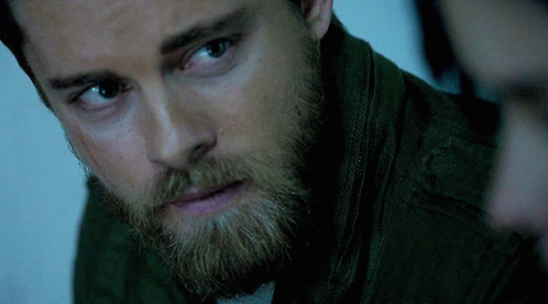 A Close Up Of A Man 'S Face With A Beard Wearing A Green Jacket GIF
