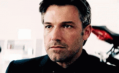 A Close Up Of A Man 'S Face With A Beard Wearing A Suit And Tie . GIF