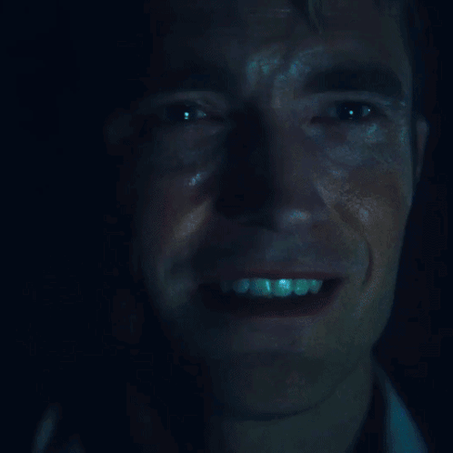 A Close Up Of A Man 'S Face With A Blue Light Shining On It GIF