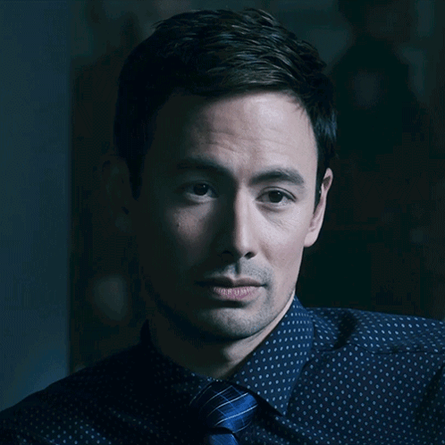 A Close Up Of A Man 'S Face With A Blue Shirt And Tie GIF