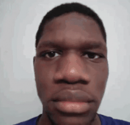 A Close Up Of A Man 'S Face With A Blue Shirt On Against A White Background . GIF