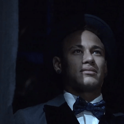 A Close Up Of A Man 'S Face With A Bow Tie And Earrings GIF