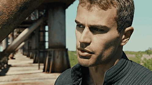 A Close Up Of A Man 'S Face With A Bridge Behind Him GIF