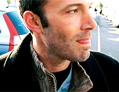 A Close Up Of A Man 'S Face With A Car Parked Behind Him GIF