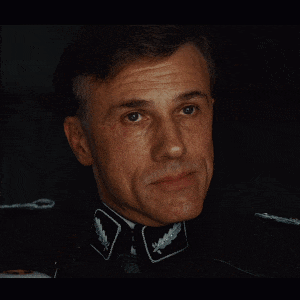 A Close Up Of A Man 'S Face With A Collar That Has A Leaf On It GIF