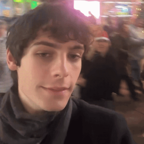 A Close Up Of A Man 'S Face With A Crowd In The Background GIF