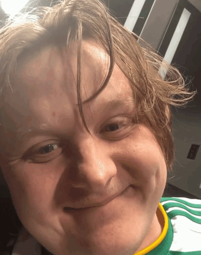 A Close Up Of A Man 'S Face With A Green And Yellow Shirt On GIF