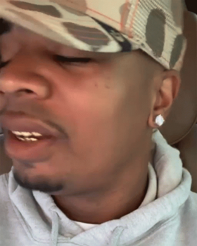 A Close Up Of A Man 'S Face With A Hat And Earrings GIF