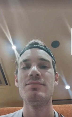 A Close Up Of A Man 'S Face With A Hat On And A Camera Around His Neck . GIF