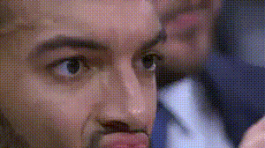 A Close Up Of A Man 'S Face With A Man In A Suit And Tie Behind Him . GIF