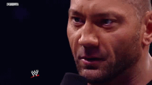 A Close Up Of A Man 'S Face With A Microphone In Front Of Him And A W Logo In The Background . GIF