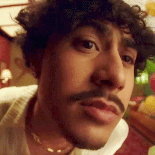 A Close Up Of A Man 'S Face With A Mustache And Curly Hair . GIF