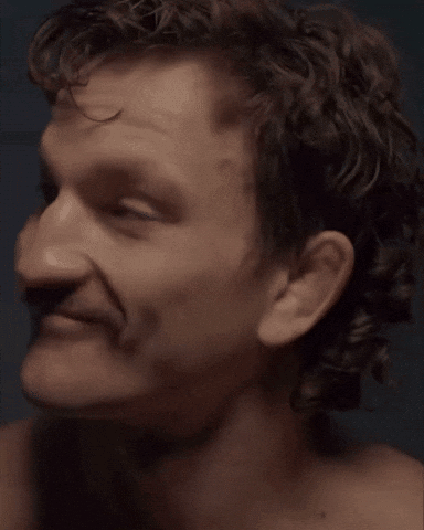 A Close Up Of A Man 'S Face With A Mustache And Curly Hair GIF