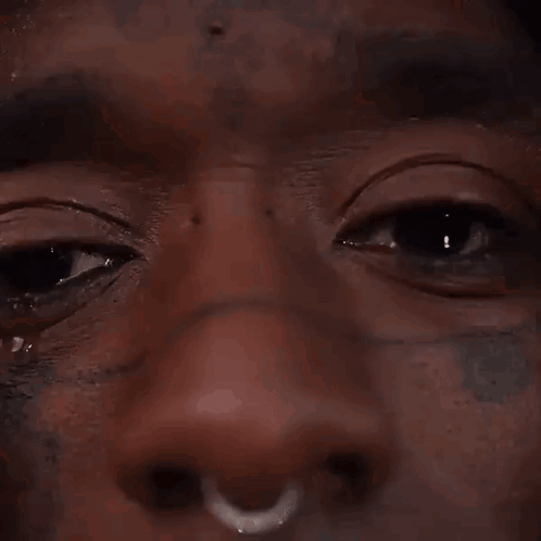 A Close Up Of A Man 'S Face With A Nose Ring And A Tear Running Down His Face . GIF
