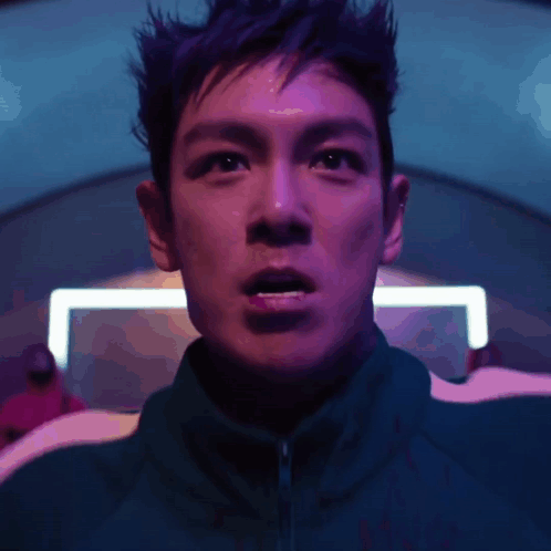 A Close Up Of A Man 'S Face With A Purple Light Behind Him GIF